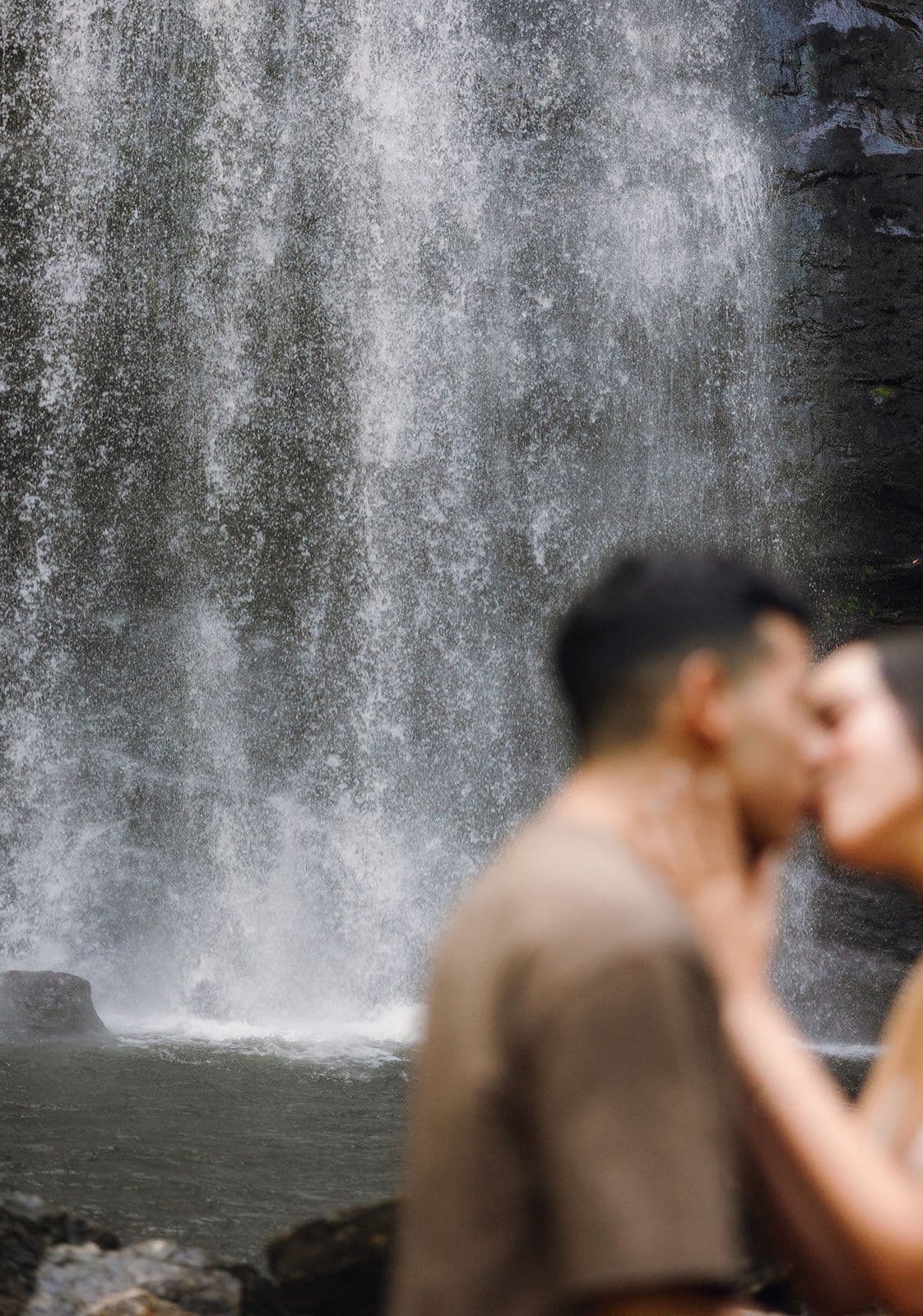 Jennifer and Christian kissing in front of a waterfall