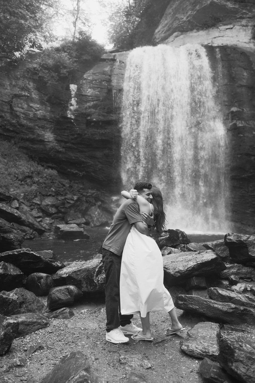 Jennifer and Christian embracing on the rocks in front of a waterfall